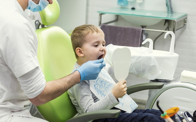 Dentiste examinant les dents du petit garçon à la clinique Problème dentaire