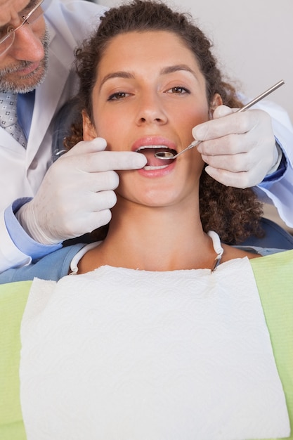 Dentiste examinant les dents d&#39;un patient dans la chaise des dentistes