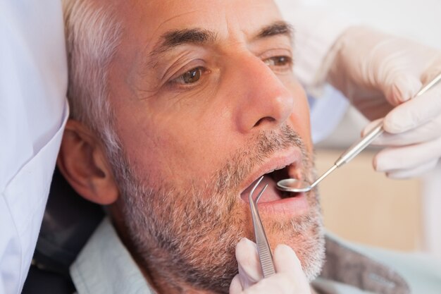 Dentiste examinant les dents d&#39;un patient dans la chaise des dentistes