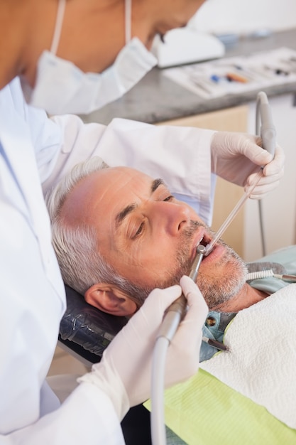 Dentiste examinant les dents d&#39;un patient dans la chaise des dentistes