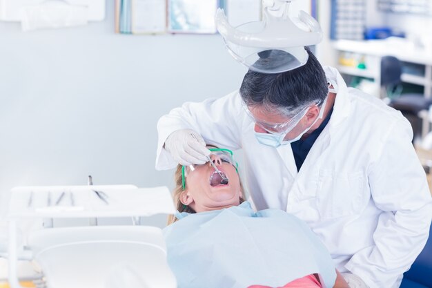 Dentiste examinant les dents d&#39;un patient dans la chaise des dentistes