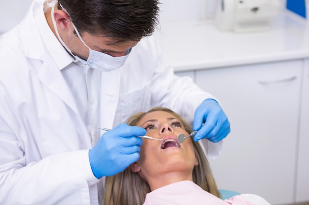 Dentiste examinant la femme à la clinique dentaire