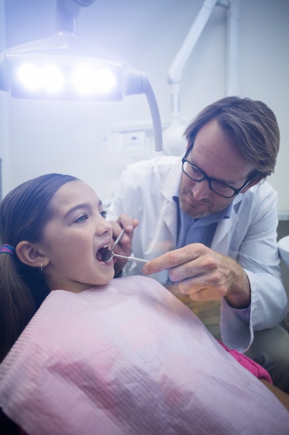 Dentiste examinant un jeune patient avec des outils