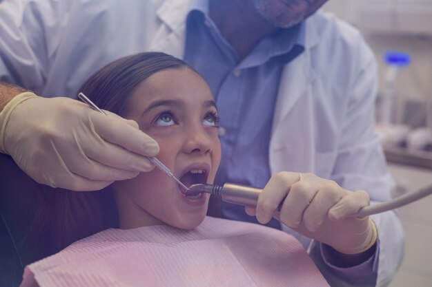 Photo dentiste examinant un jeune patient avec des outils