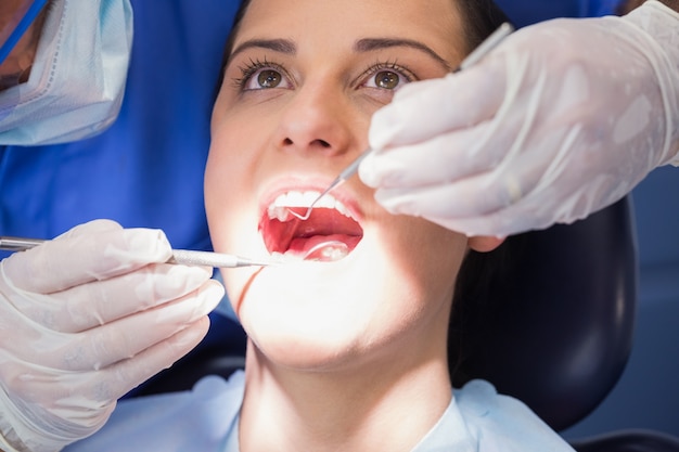 Dentiste examinant un patient avec un miroir d&#39;angle et une sonde à faucille
