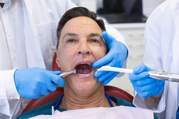 Dentiste examinant un patient de sexe masculin avec des outils