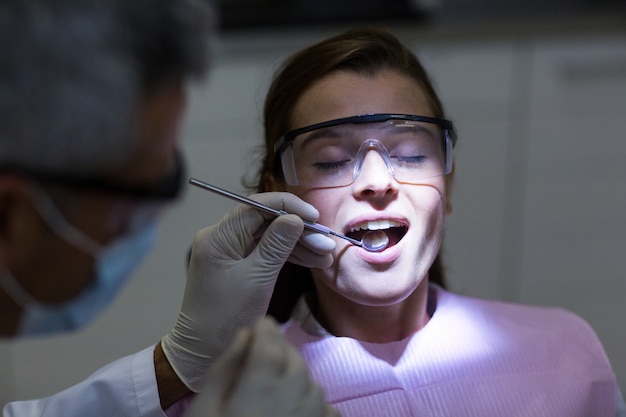 Dentiste examinant une patiente avec des outils