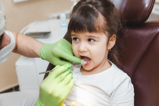 Le dentiste examine les dents de l'enfant dans le concept de médecine et de dentisterie du fauteuil dentaire