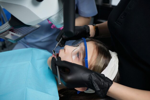 Le dentiste examine les dents de l'enfant avec un microscope Matériel dentaire professionnel