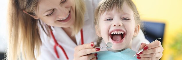 Le dentiste examine les dents d'une fille souriante. Traitement dentaire sans concept de douleur