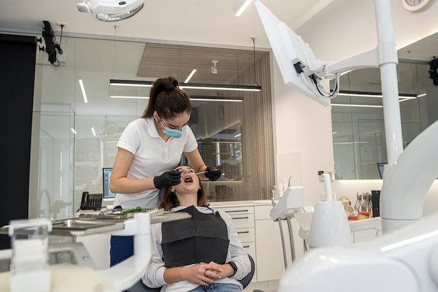 Une dentiste examine les dents d'une patiente avec des outils en dentisterie