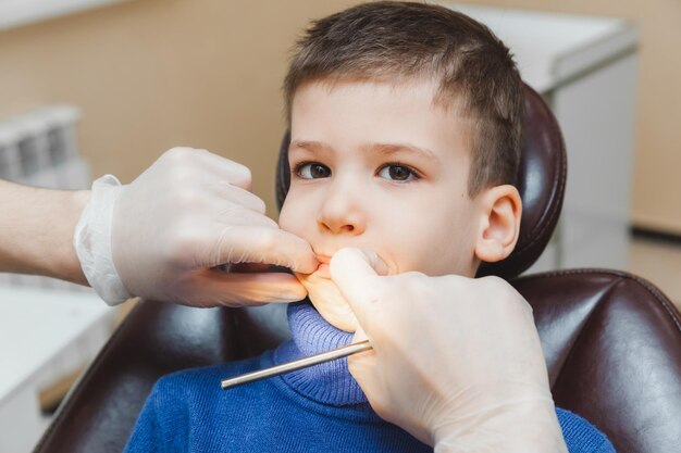 Le dentiste examine les dents d'un petit garçon un patient dans une clinique dentaire