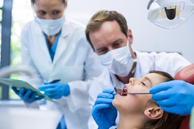 Un dentiste examine un jeune patient avec des outils.