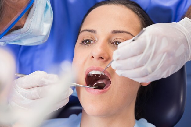 Dentiste examine un patient avec un miroir angulaire et une sonde faucille