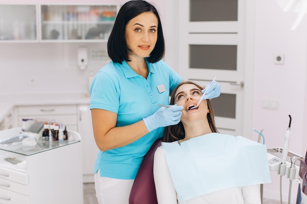Une dentiste examine son patient dans un fauteuil dentaire