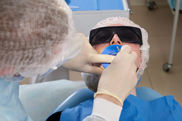 Dentiste faisant un traitement dentaire sur une patiente. Dentiste examinant les dents d'un patient dans un bureau de dentisterie moderne