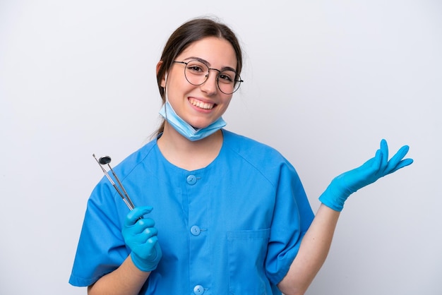 Dentiste femme caucasienne tenant des outils isolés sur fond blanc tendant les mains sur le côté pour inviter à venir