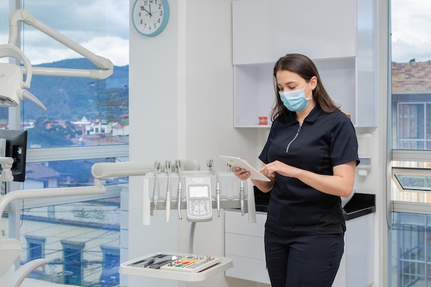 Dentiste femme à côté de l'équipement de la clinique dentaire tenant une tablette Concept de clinique dentaire