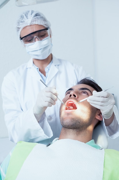 Dentiste femme examinant les dents de l&#39;homme