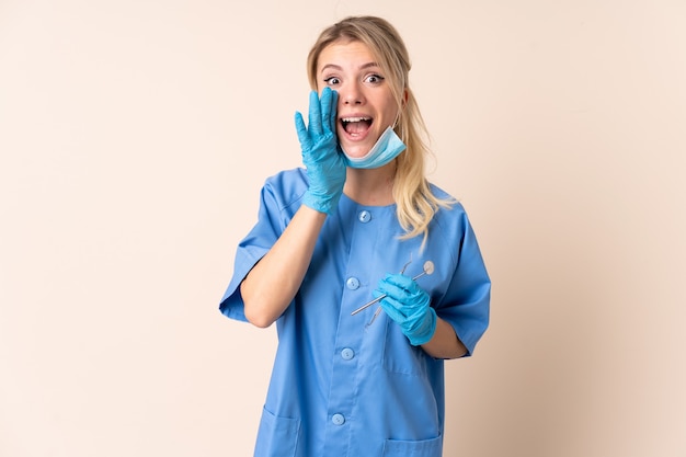 Dentiste femme tenant des outils sur des cris isolés avec la bouche grande ouverte