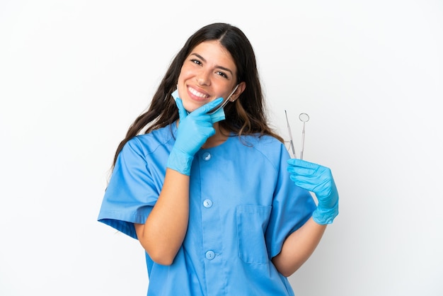 Dentiste femme tenant des outils sur fond blanc isolé heureux et souriant