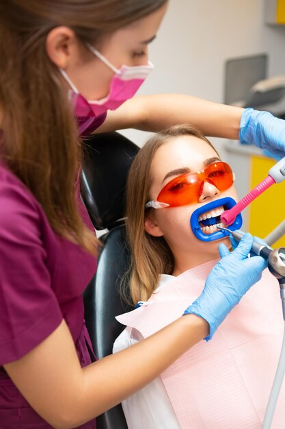 Dentiste en gants effectuant le nettoyage des dents à partir du détecteur