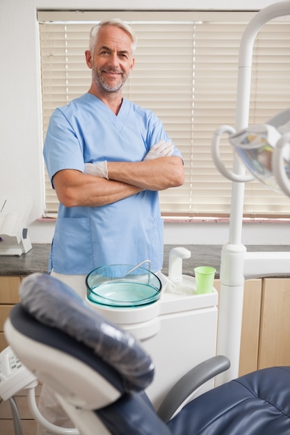 Dentiste en gommages bleus, souriant à la caméra