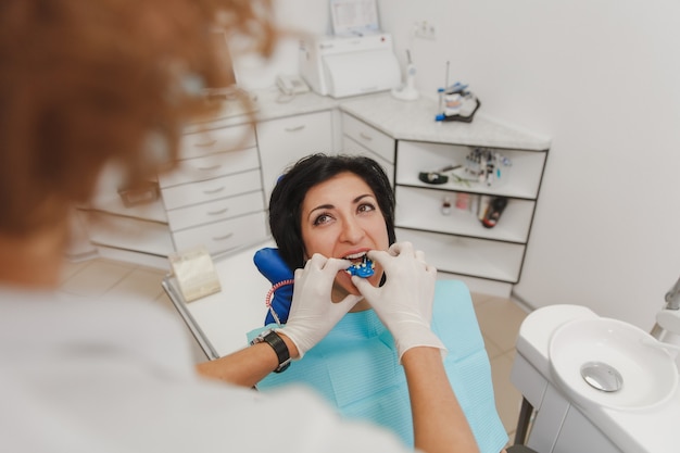 La dentiste installe dans la bouche du patient un appareil pour fabriquer une dent moulée