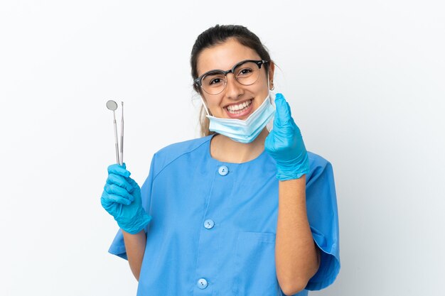Dentiste de jeune femme tenant des outils isolés sur fond blanc faisant un geste d'argent