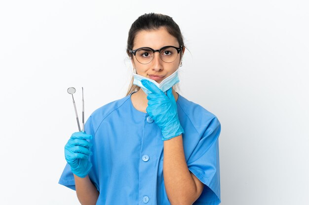 Dentiste de jeune femme tenant des outils isolés sur la pensée de fond blanc