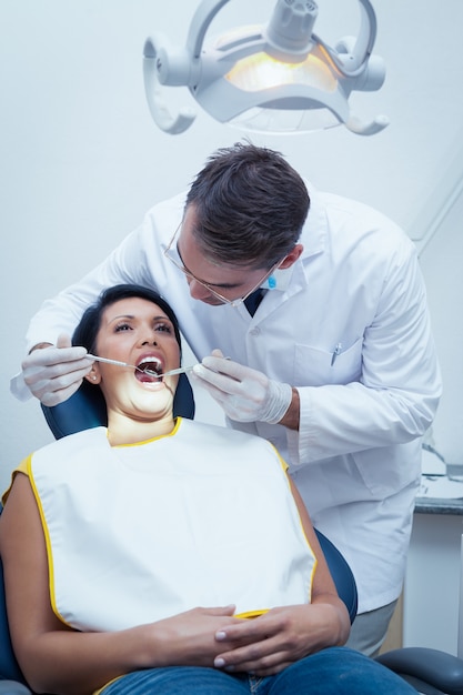 Dentiste mâle examinant les dents de la femme
