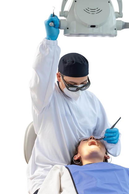 Dentiste masculin en uniforme fixant la lampe pendant qu'un patient est allongé sur la chaise avec la bouche ouverte Concept de clinique dentaire