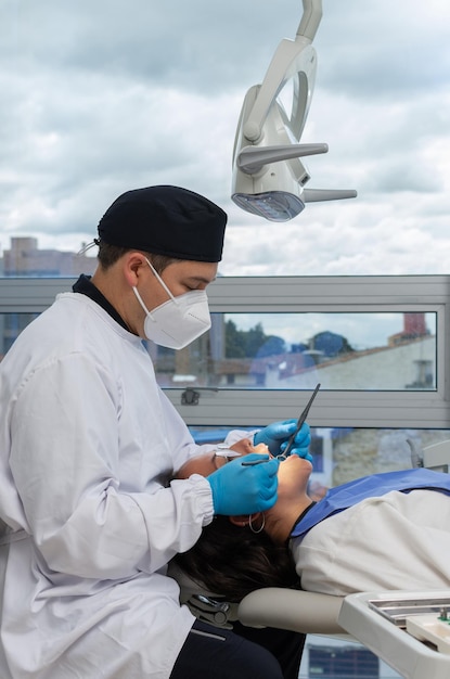 Dentiste masculin en uniforme et masque facial lors d'une intervention dentaire sur une femme Concept de clinique dentaire