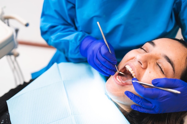 Dentiste méconnaissable faisant un examen dentaire de routine à l'aide d'un miroir buccal et d'une excavatrice