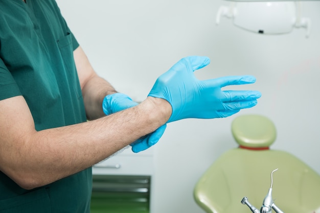 Le dentiste met des gants avant le travail