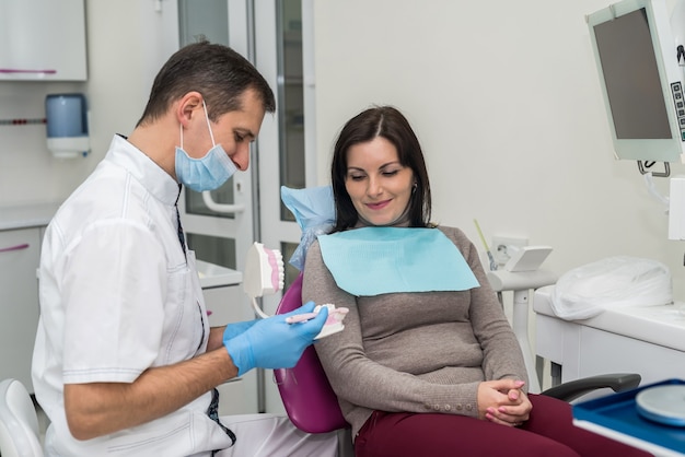 Dentiste montrant comment nettoyer les dents directement au patient