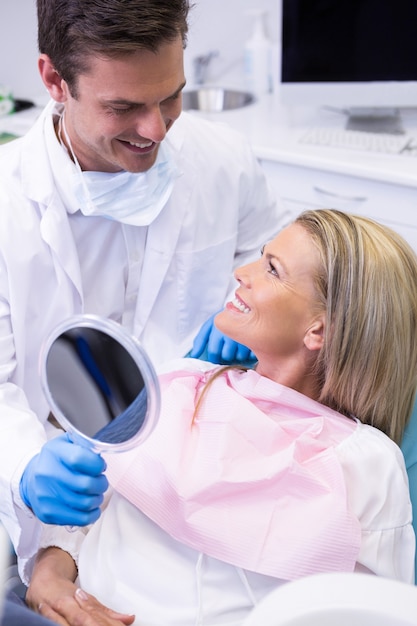 Dentiste montrant un miroir à un patient heureux