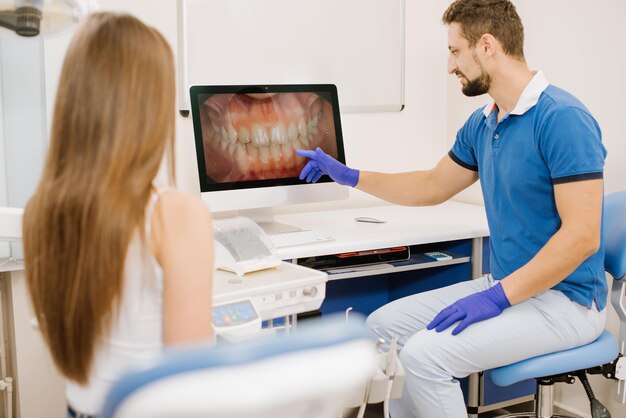 Un dentiste montrant une photo de dents au patient à l'écran