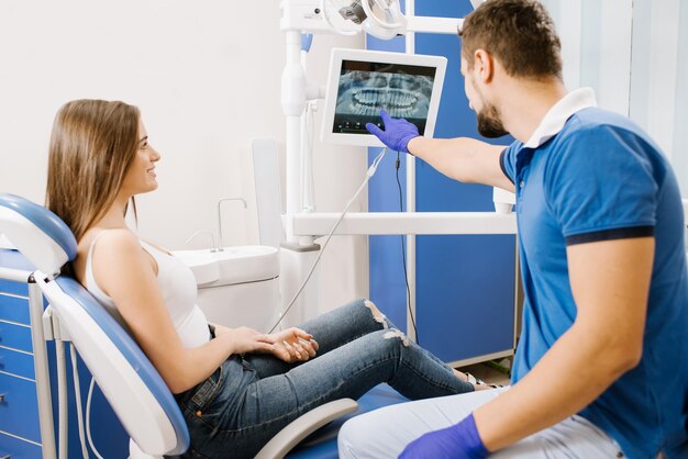 Un dentiste montrant une photo de dents au patient à l'écran