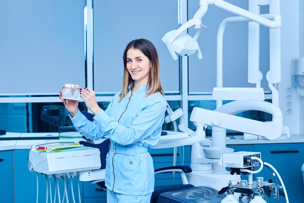 Le dentiste montre le modèle d'implant dans sa main au bureau ou à la clinique