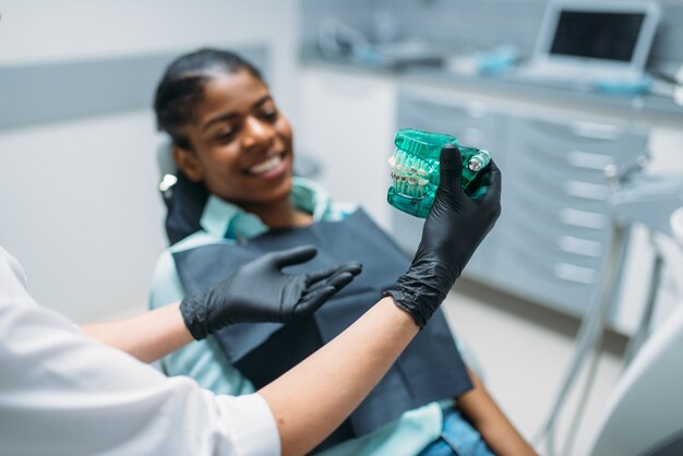 Dentiste montre des prothèses au patient dans une clinique dentaire