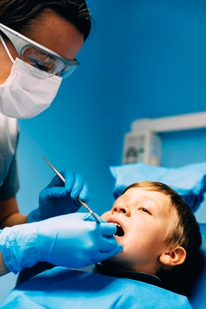 Le dentiste opère un garçon joyeux dans une clinique médicale.