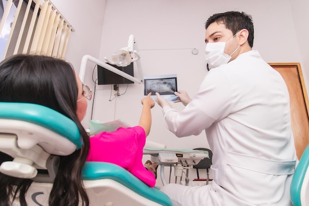 Photo le dentiste parle à son patient en expliquant une radiographie dentaire.