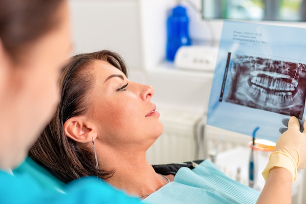 Photo un dentiste et un patient regardent une image radiographique