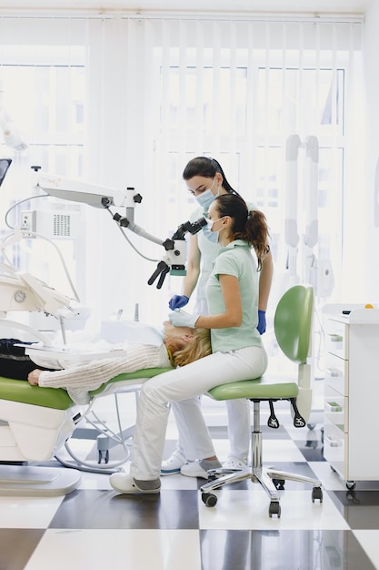 Un dentiste et un patient regardent un microscope.