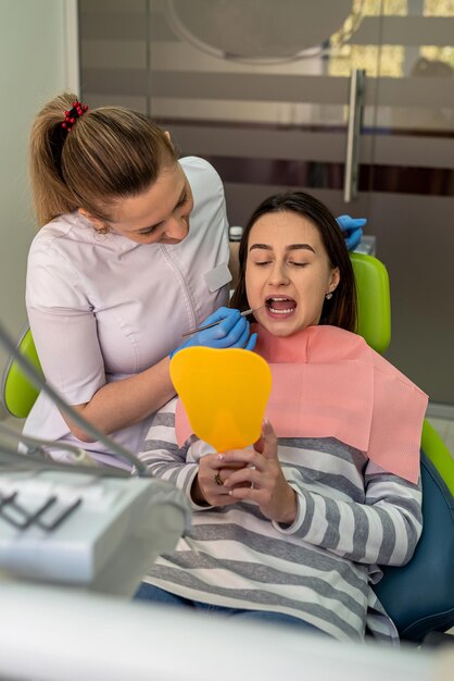 Photo le dentiste et le patient se regardent dans le miroir après le traitement de la carie