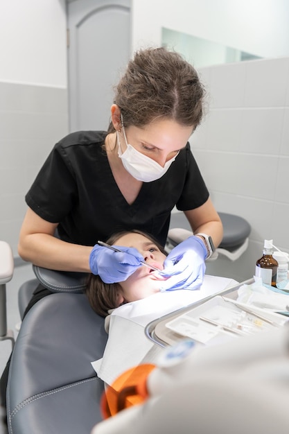 Photo un dentiste pédiatrique effectue un examen dentaire avant le traitement des caries