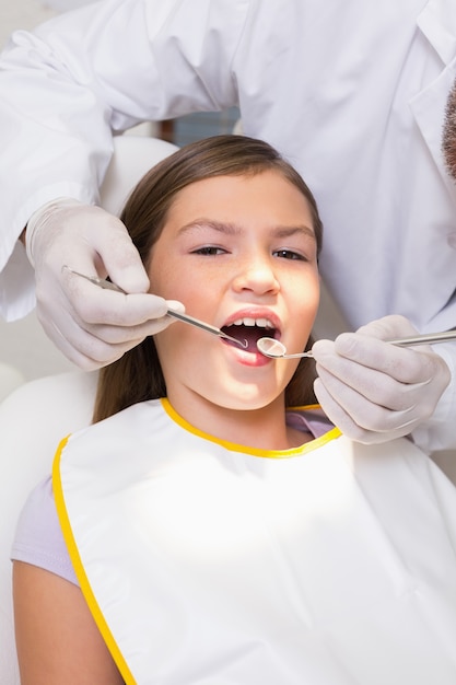 Dentiste pédiatrique examinant les dents d&#39;un patient dans la chaise des dentistes