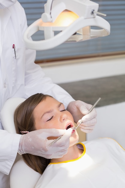 Dentiste pédiatrique examinant les dents d&#39;un patient dans la chaise des dentistes