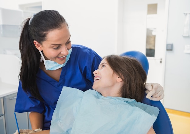 Dentiste pédiatrique gai avec un jeune patient souriant